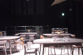 中二階 休憩コーナーの写真。木製の丸テーブルと椅子が配置され、上からA2エリアの展示物が見られます。