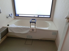 ユニバーサルルーム和室のお風呂の写真。浴室内は広く、浴槽は低く、手すりが設置されています