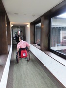客室廊下の写真。廊下はカーペットで車いすの通行できる幅あり、渡り廊下両側ガラスで明るく開放的です