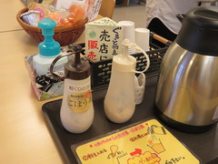 観光交流休憩棟の飲食もできるスペースの写真。お茶や水が置かれ、試供品は売店で購入できます