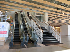 ２階図書館へのエスカレーターと階段の写真。横にエレベーターもあります