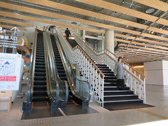 2階図書館へのエスカレーターと階段の写真。横にエレベーターもあります