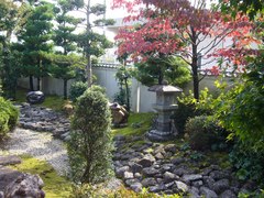 美しい庭の写真。塀に囲まれ灯籠や置物、植栽が調和しています