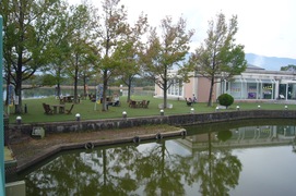 パークセンターホールの写真。緑の木々に囲まれ水面に映る景色は時間がゆっくり流れています