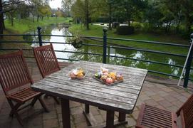 テーブルと椅子の写真。緑の木々に沿って水路が流れ、所々に休憩のできる場所があります