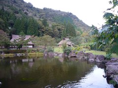 景色に溶け込む池と古民家の写真。山々を背景に池の周りに古民家が立ち並んでいます
