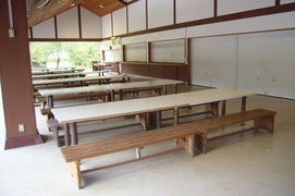 鶴見亭 食事スペースの写真。長テーブルと可動式の長椅子で、車いすも利用できる広いスペースがあります