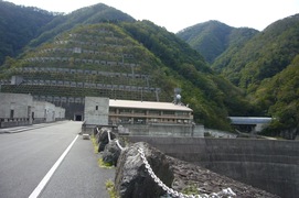 徳山ダム管理所への眺めの写真。堤頂の上の通路は広く、ダムの周辺は山々に囲まれているのが良くわかります