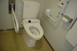 車いすマークのトイレの内部の写真。おむつ交換ベッド、手すり、温水、呼出ボタンも備えられた広いトイレ