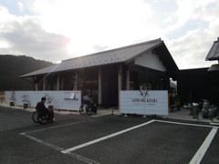 里山きさらの外観の写真。周りを山々に囲まれ、白い板塀に囲まれた木造平屋のお店です