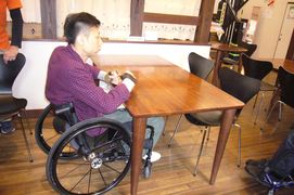 カフェのテーブルの写真。木製のテーブルは、車いすも膝が入りちょうど良い高さになっています