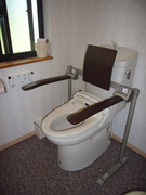 車いすマークのトイレの写真。跳ね上げ式の手すりと背もたれがあります