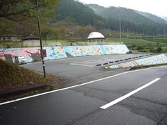 霞間ヶ渓公園大駐車場の写真。舗装され、壁には桜が描かれています