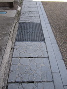 道路の端の側溝の写真。側溝は蓋、グレーチングも細かく、車いすも大丈夫。