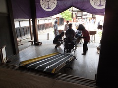 車いすはスロープで入館できますの写真。スロープを設置してもらいます、勾配が急なので手伝ってもらいます。