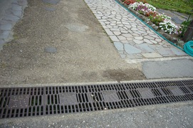 合掌造りの模様のグレーチングの写真。荻町公園内の側溝のグレーチングは、合掌造りの模様です。網目も細かく、車いすやベビーカーでも安全に通れます。