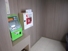 AEDの写真。一階ロビーの公衆電話横にあります