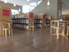 本棚の写真。床はフローリングで本棚の間の通路は広く椅子も置かれ快適に過ごせます