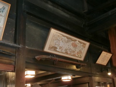 江戸時代からの歴史を感じる店内の写真。黒光りする梁と漆喰の黒壁に掲げられた火縄銃